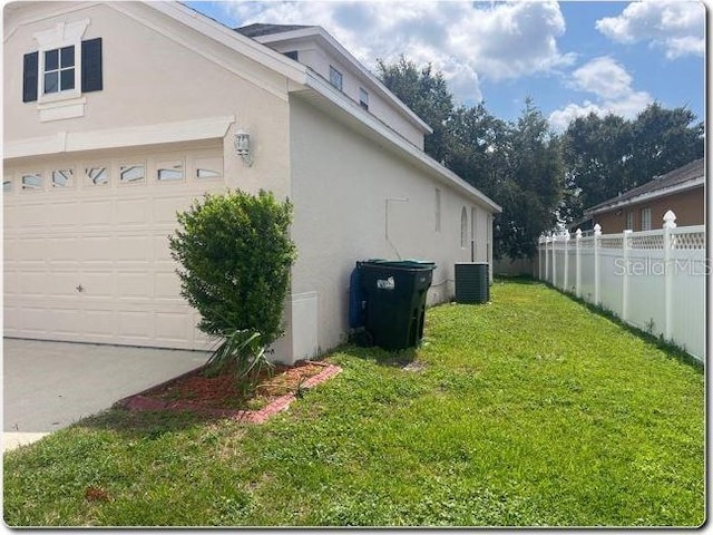 view of property exterior featuring a yard, a garage, and central air condition unit