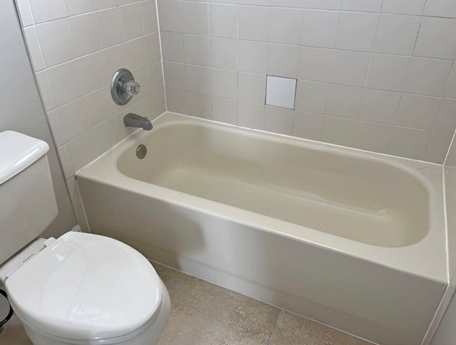 bathroom featuring tiled shower / bath combo and toilet