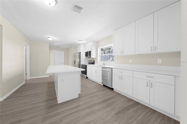 kitchen with white cabinets, appliances with stainless steel finishes, sink, and a kitchen island