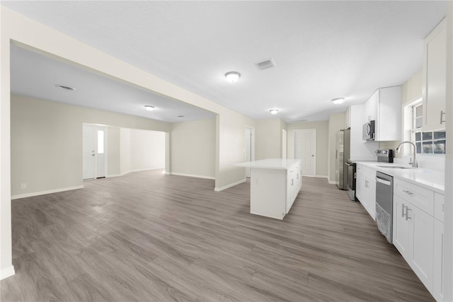 kitchen featuring hardwood / wood-style flooring, sink, white cabinets, and a kitchen island