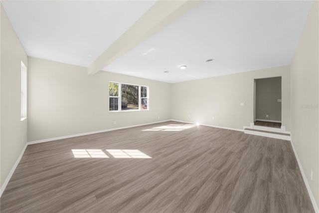 spare room featuring dark wood-type flooring and beamed ceiling