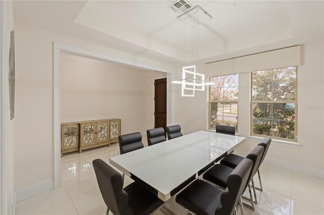 dining room with a raised ceiling and light tile patterned flooring