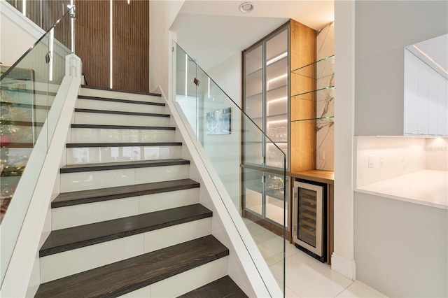 staircase featuring tile patterned floors, beverage cooler, and bar area