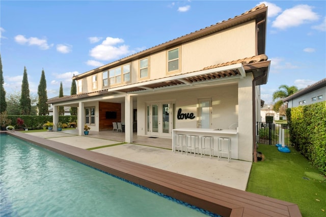 rear view of house with a patio, a fenced in pool, and an outdoor bar