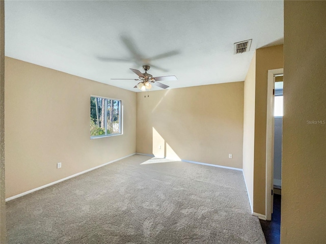 carpeted spare room featuring ceiling fan and a wealth of natural light