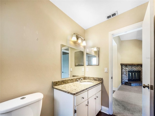 bathroom with vanity, toilet, and a fireplace