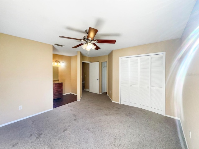 unfurnished bedroom with connected bathroom, dark carpet, and ceiling fan