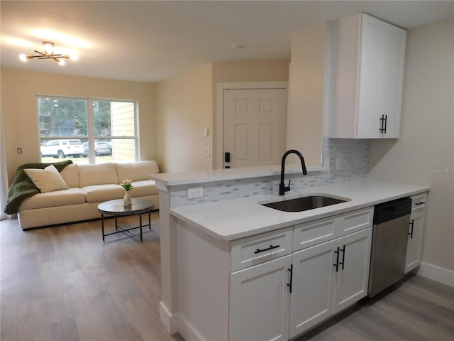 kitchen with dishwasher, sink, kitchen peninsula, decorative backsplash, and white cabinets