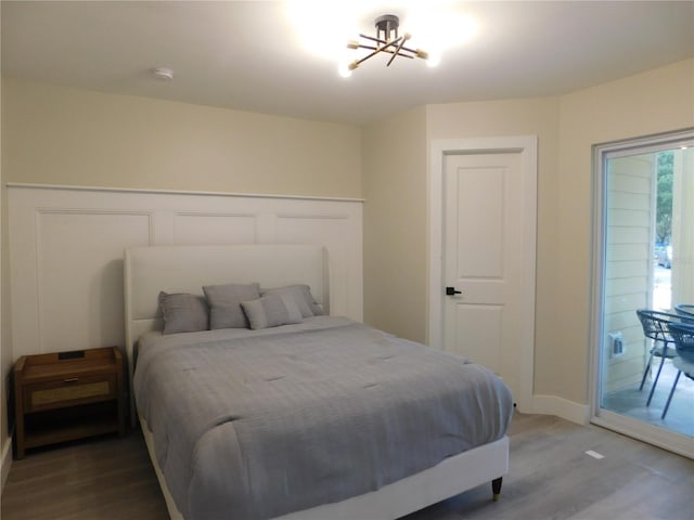 bedroom featuring hardwood / wood-style floors, access to exterior, and a chandelier