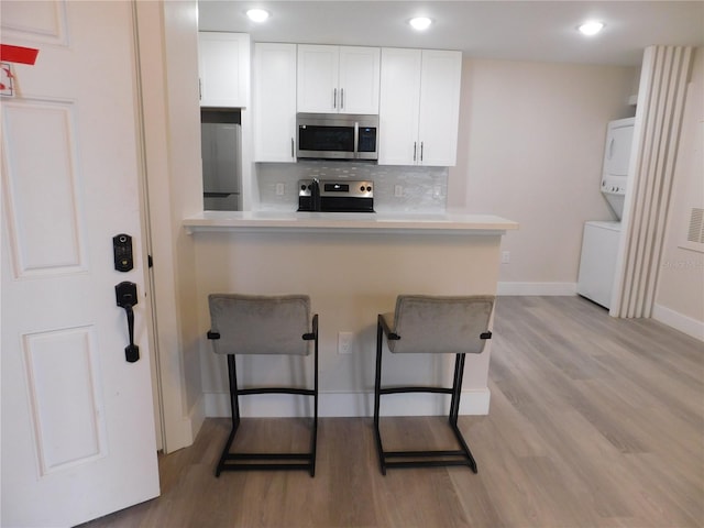 kitchen featuring a breakfast bar area, kitchen peninsula, white cabinetry, and stainless steel appliances