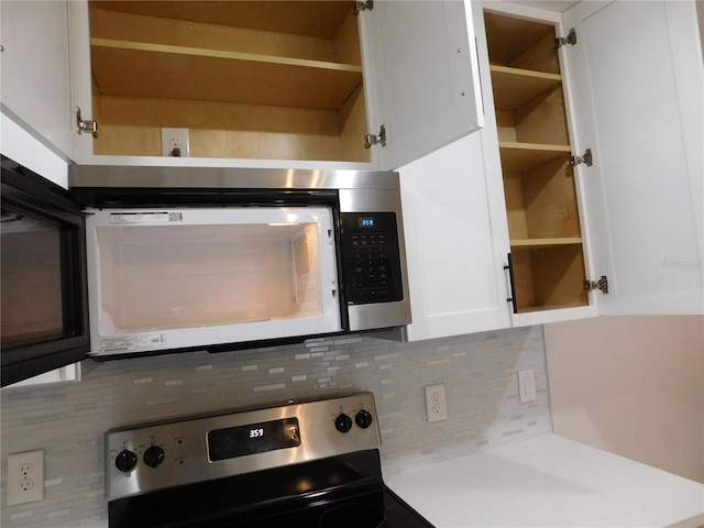 kitchen featuring decorative backsplash, white cabinetry, and range