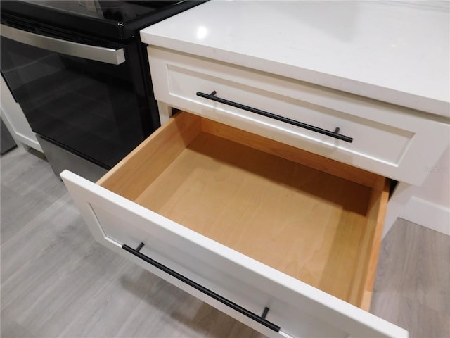 room details with white cabinets and black range with electric cooktop