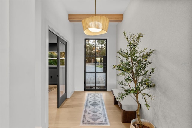 interior space with beam ceiling, light hardwood / wood-style flooring, and french doors