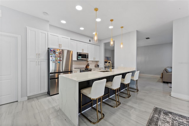 kitchen with white cabinetry, stainless steel appliances, tasteful backsplash, decorative light fixtures, and a breakfast bar