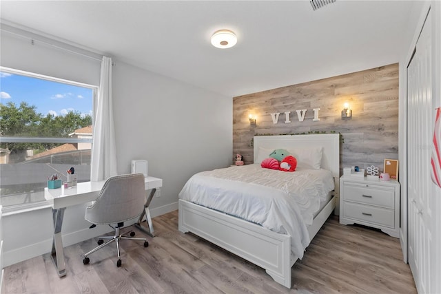 bedroom with wood walls and light hardwood / wood-style flooring