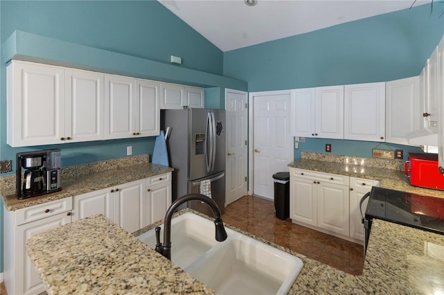 kitchen with white cabinets, stainless steel fridge, light stone countertops, and sink