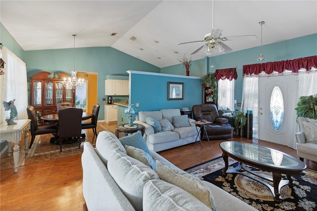 living room with ceiling fan with notable chandelier, wood-type flooring, and lofted ceiling