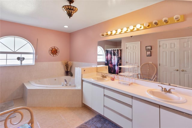 bathroom featuring tile patterned flooring, vanity, a healthy amount of sunlight, and a relaxing tiled tub