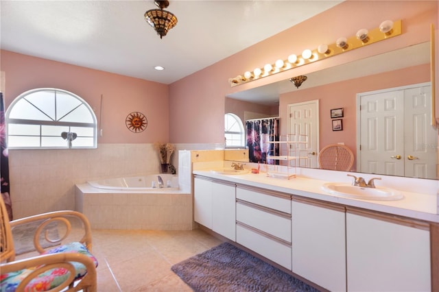 bathroom with tile patterned flooring, vanity, and a relaxing tiled tub