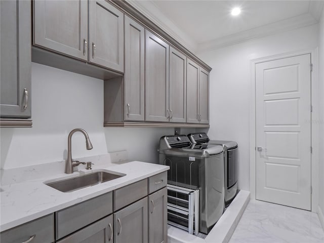 laundry area with washing machine and dryer, sink, cabinets, and ornamental molding