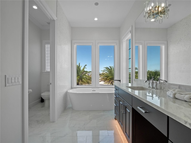 bathroom featuring vanity, toilet, a bathtub, and a notable chandelier