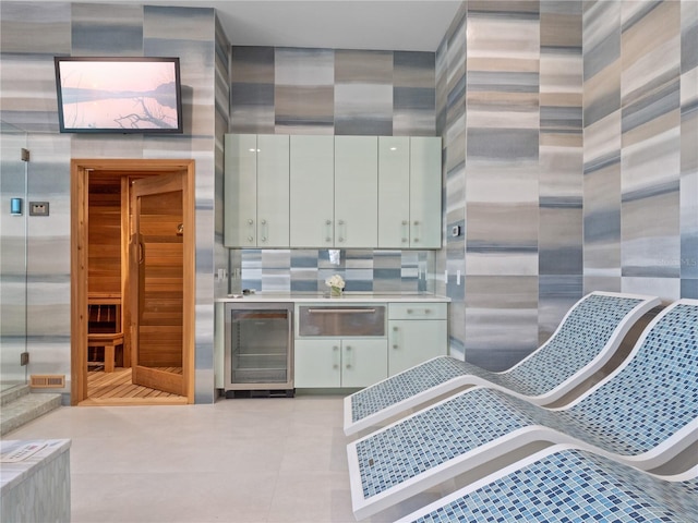 kitchen featuring white cabinets, light tile patterned flooring, a towering ceiling, and beverage cooler