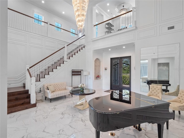 entrance foyer with a notable chandelier, a towering ceiling, and french doors