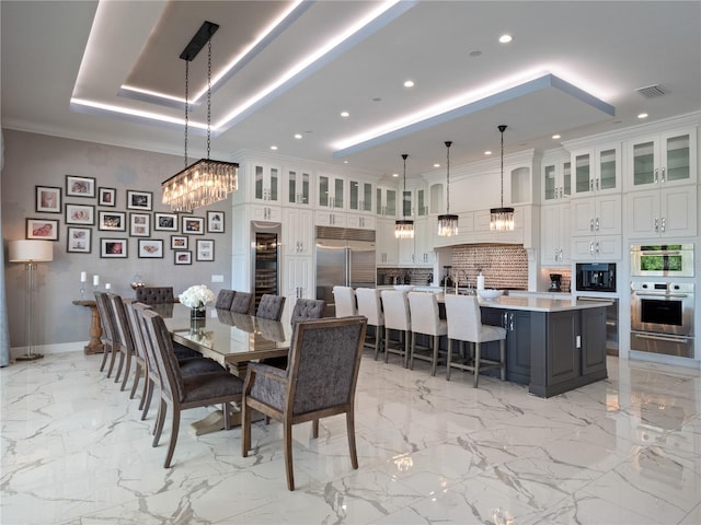 dining area with a notable chandelier, crown molding, beverage cooler, and a tray ceiling