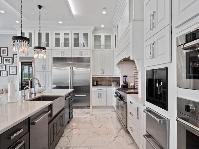 kitchen featuring white cabinets, high quality appliances, light stone countertops, and hanging light fixtures