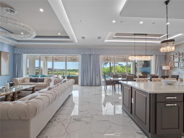 living room featuring a notable chandelier, ornamental molding, and a tray ceiling