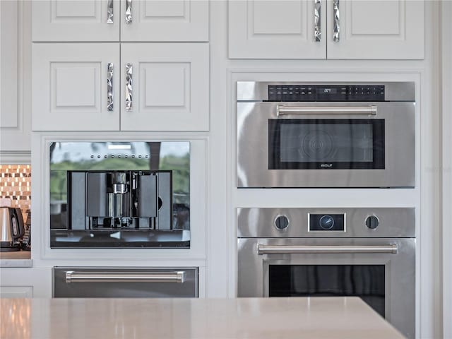 room details with backsplash, white cabinetry, and double oven