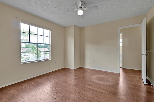 empty room with ceiling fan, wood-type flooring, and a textured ceiling