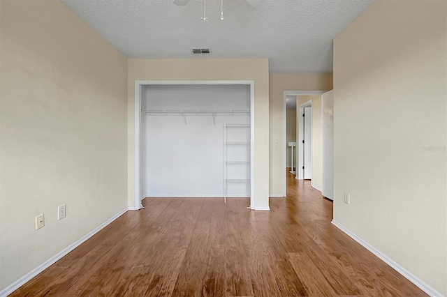 unfurnished bedroom featuring a closet, wood-type flooring, and a textured ceiling