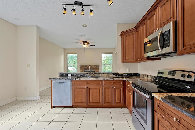 kitchen with sink, ceiling fan, dark stone countertops, light tile patterned floors, and stainless steel appliances