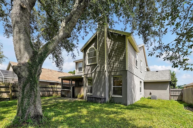 rear view of property featuring a yard and cooling unit