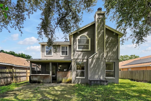 back of property with a sunroom and a yard