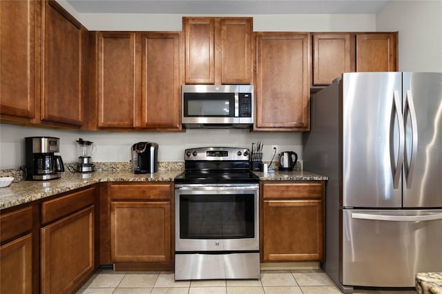 kitchen featuring appliances with stainless steel finishes, light stone counters, and light tile patterned flooring