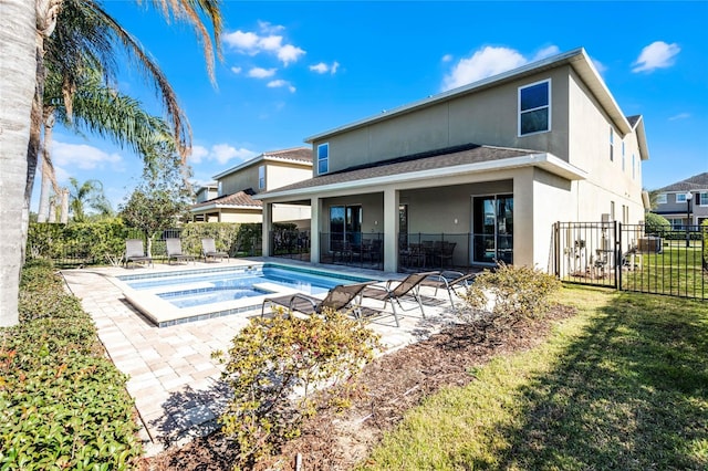 back of property with a patio area, a yard, and a pool with hot tub