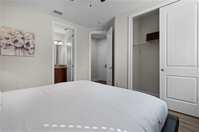 bedroom with ceiling fan, dark hardwood / wood-style flooring, connected bathroom, and a closet