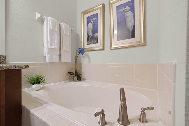 bathroom featuring a relaxing tiled tub and vanity