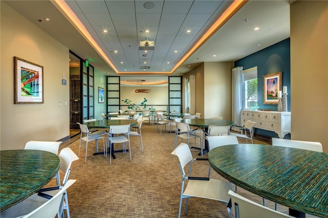 carpeted dining space with a raised ceiling