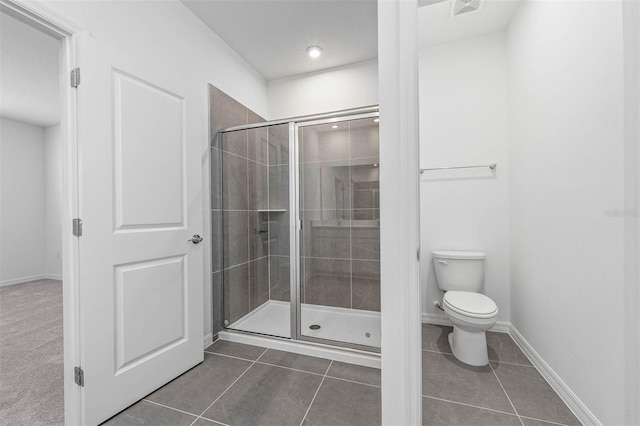 bathroom with tile patterned flooring, a shower with shower door, and toilet