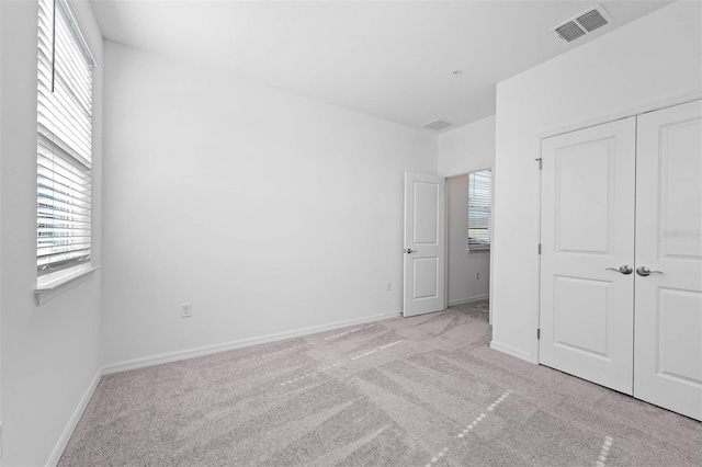 unfurnished bedroom with a closet and light carpet