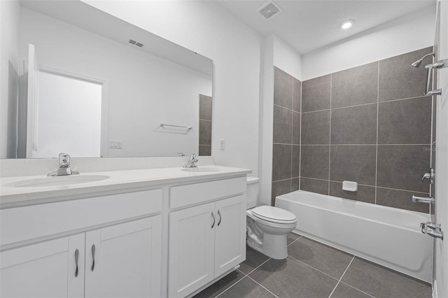 full bathroom featuring tile patterned flooring, tiled shower / bath, vanity, and toilet