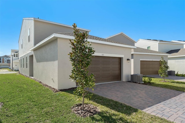 view of side of property with a garage, a yard, and central air condition unit