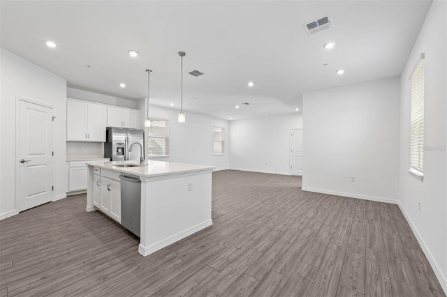 kitchen with an island with sink, appliances with stainless steel finishes, and white cabinets