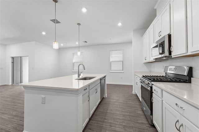 kitchen with appliances with stainless steel finishes, pendant lighting, an island with sink, sink, and white cabinets