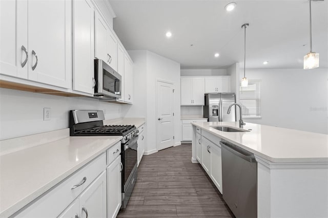 kitchen featuring hanging light fixtures, appliances with stainless steel finishes, sink, and white cabinets