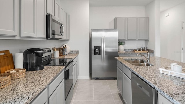 kitchen with light stone counters, sink, light tile patterned floors, and stainless steel appliances