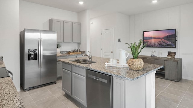 kitchen with appliances with stainless steel finishes, gray cabinetry, sink, light tile patterned floors, and an island with sink